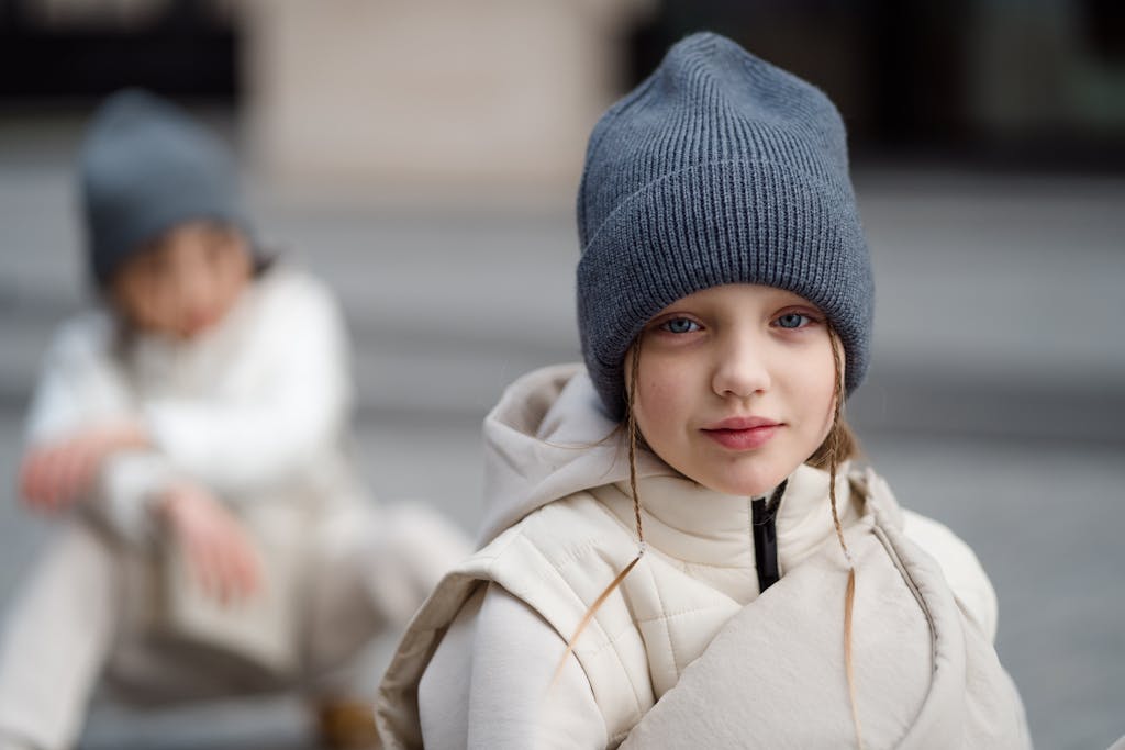 Portrait of a smiling child wearing a beanie and white jacket, outdoors in winter.
